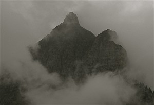 A peak in the Glacier Natioanl Forest looks ominous wrapped in a shroud of clouds.